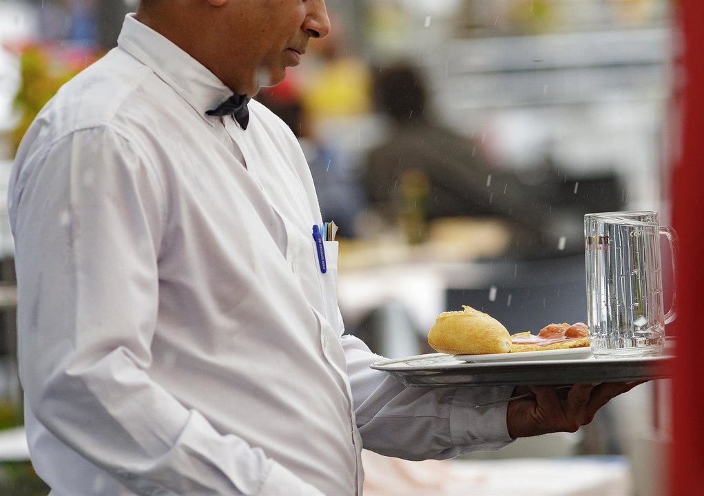 Un camarero porta una bandeja en un bar de Madrid.